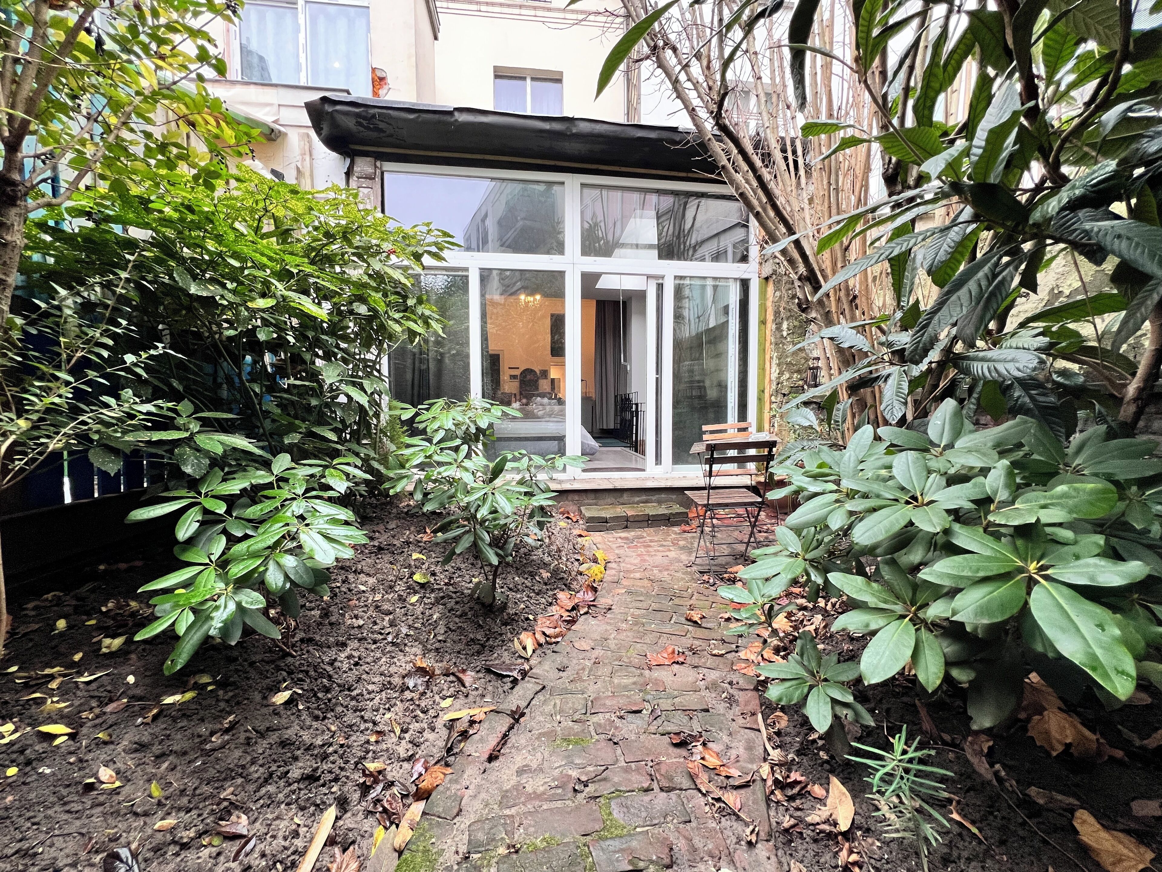 A garden pathway leading to a glass door entrance of a building.