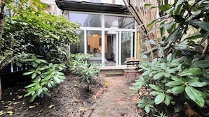 Un chemin de jardin menant à une entrée de bâtiment avec une porte en verre.
