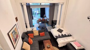 Une chambre d’hôtel moderne, équipée d’un canapé, d’un lit, d’une table basse en bois et offrant une vue sur le jardin par la fenêtre.
