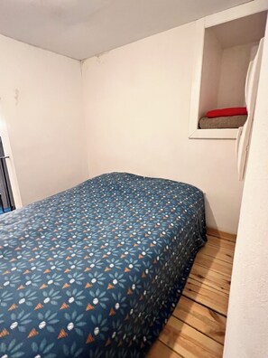 A small, narrow room with a single bed, a window with a red cushion, and a wooden floor. - Chic Comfortable Loft and Natural Light (Brussels)