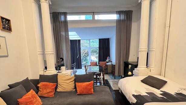 Une chambre d’hôtel avec un canapé, un lit, une table basse en bois et une vue sur la salle à manger.