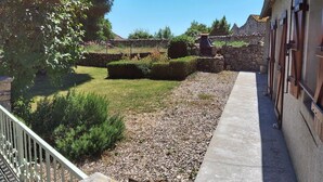 A courtyard with a stone wall, a gravel path, and a building with a metal gate. - Gite du Fourbas - renovated in 2025 - with swimming pool (Belmont-Sainte-Foi)