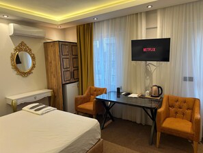 A hotel room with a bed, two armchairs, a desk, a flat-screen TV, and a minibar. - Ananas Suite (Istanbul)