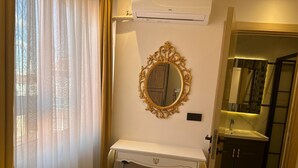 A hotel room with a white desk, a gold-framed mirror, and a bathroom with a sink and mirror. - Ananas Suite (Istanbul)