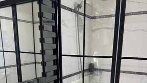 Casa de banho moderna com uma pia branca, cabine de chuveiro em vidro e um espelho grande.