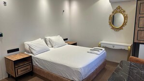 A neatly arranged hotel room with a bed, bedside tables, a vanity with a mirror, and an air conditioning unit. - Ananas Suite (Istanbul)