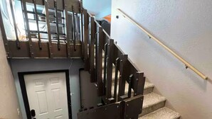 A staircase with a metal railing, carpeted steps, and a door at the bottom. - 3-bdrm condo - 1 block to Main Street - Breckenridge - perfect for families (Breckenridge)
