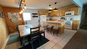 A compact kitchen with wooden cabinets, a central island, and a dining area with a table and chairs. - 3-bdrm condo - 1 block to Main Street - Breckenridge - perfect for families (Breckenridge)