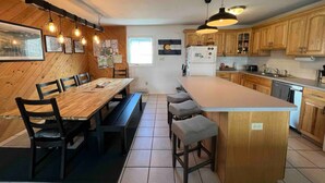 A kitchen with wooden cabinets, a central island, a dining table with chairs, pendant lighting, and a refrigerator. - 3-bdrm condo - 1 block to Main Street - Breckenridge - perfect for families (Breckenridge)