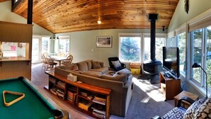 A cozy living room with a pool table, a fireplace, and a dining area with chairs and a table.