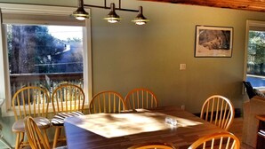 A dining area with a wooden table and chairs, a chandelier, and a framed picture on the wall.