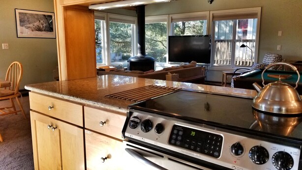 A kitchen with a large countertop, a stove, and a kettle.