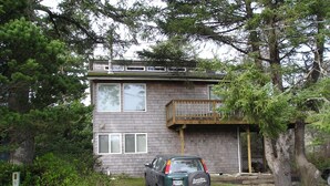 A two-story house with a balcony and a parked car in front.