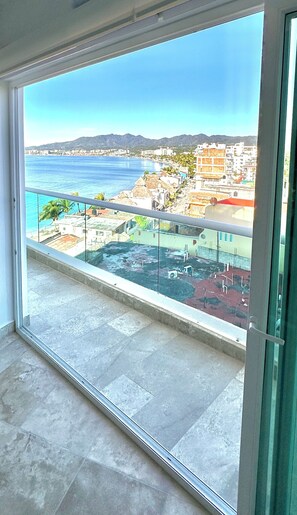 A balcony with a clear view of a coastal cityscape, including buildings and a beach.