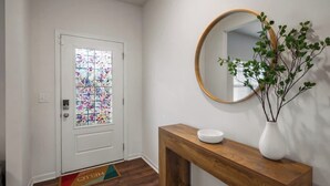 A hallway with a white door, a wooden console table with a white bowl, a round mirror, and a potted plant. - Spacious Farragut 5BR Family|Group Getaway near UT (Knoxville)