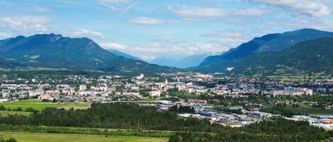 A town nestled between mountains with a mix of residential and commercial buildings, surrounded by green fields and a church.