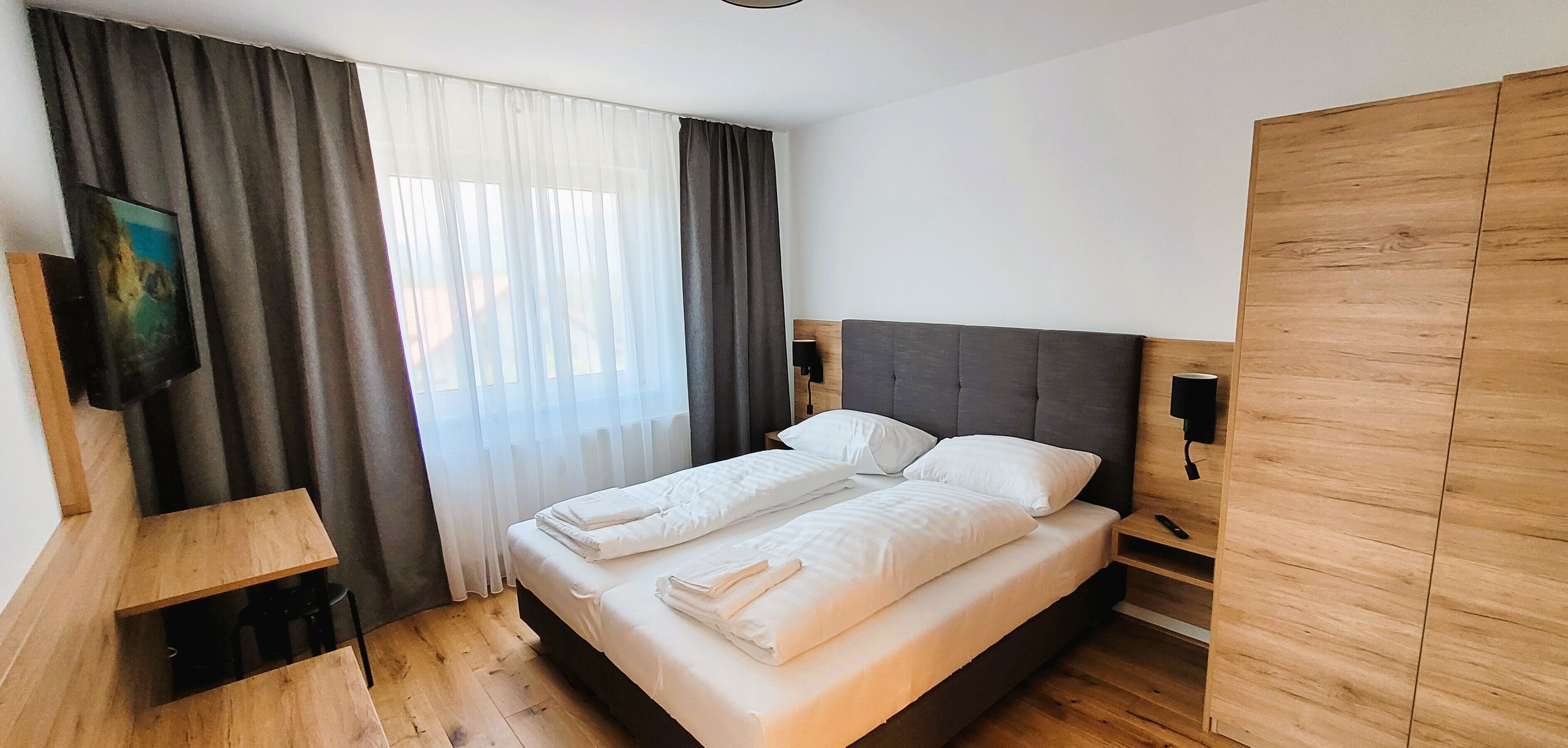 A neatly made bed with white linens, a wooden headboard, and a bedside table with a lamp.