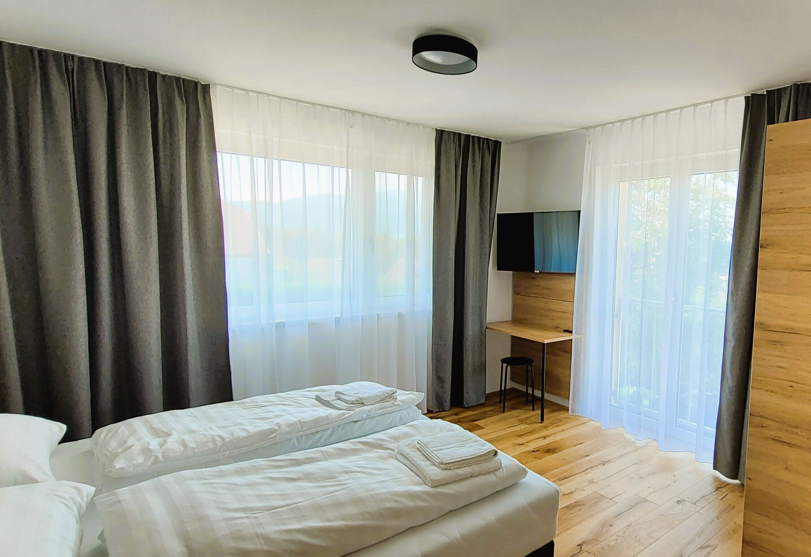 Een moderne hotelkamer met een bed, een bureau en een televisie.