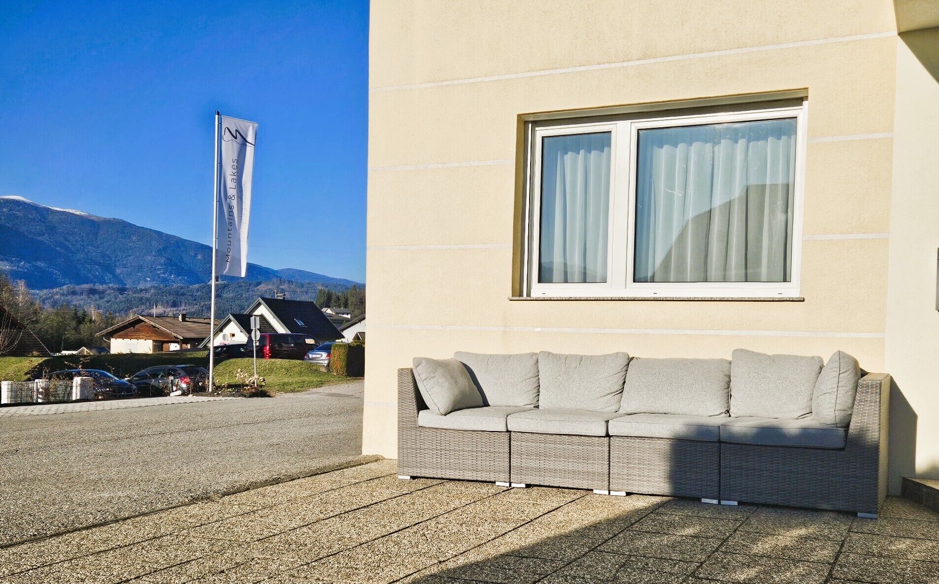 A modern building with a large window and a wicker sofa outside.