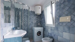 A bathroom with a glass shower enclosure, a washing machine, a sink, and a toilet. - Profumo di Mare - Two Bedroom Apartment, Sleeps 4 (Olbia)