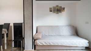Un salon minimaliste avec un canapé gris, une petite table et une chaise.