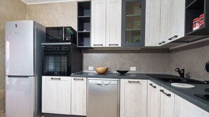 A modern kitchen with a refrigerator, oven, dishwasher, and a microwave.