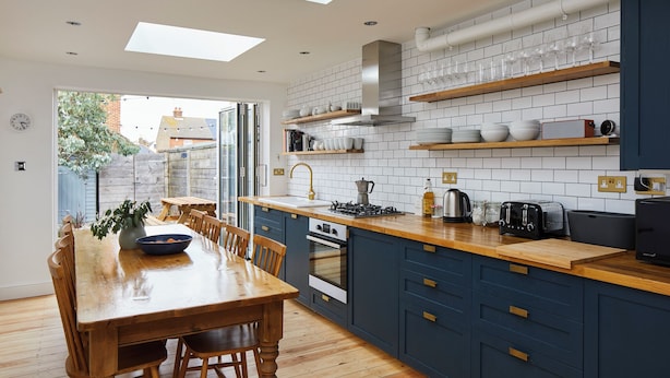 A modern kitchen with a wooden dining table, built-in cabinets, and a skylight.