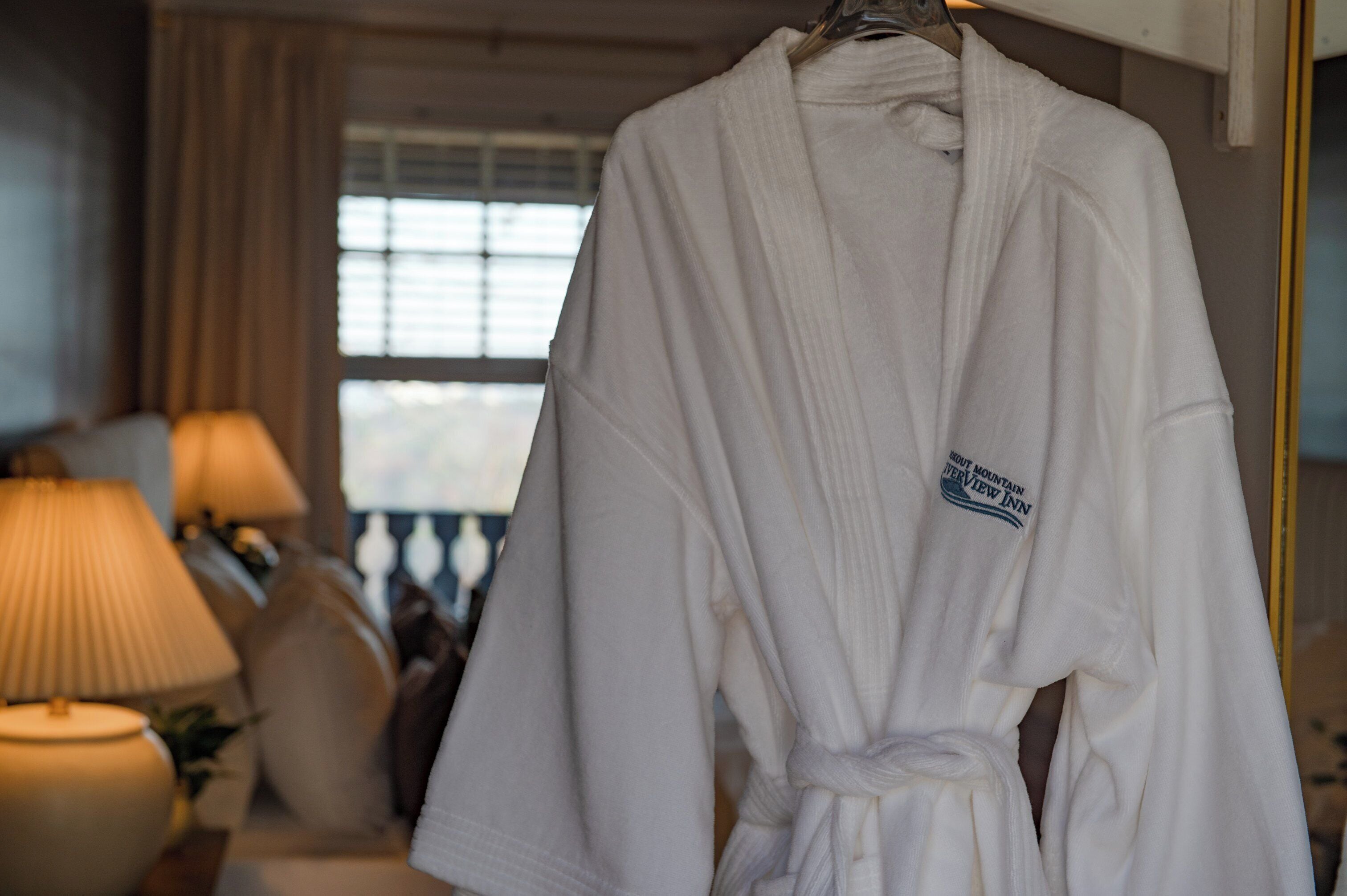 Un peignoir blanc est suspendu à un porte-manteau, et une étiquette indique : « GREAT MOUNTAIN OVERVIEW INN ».
