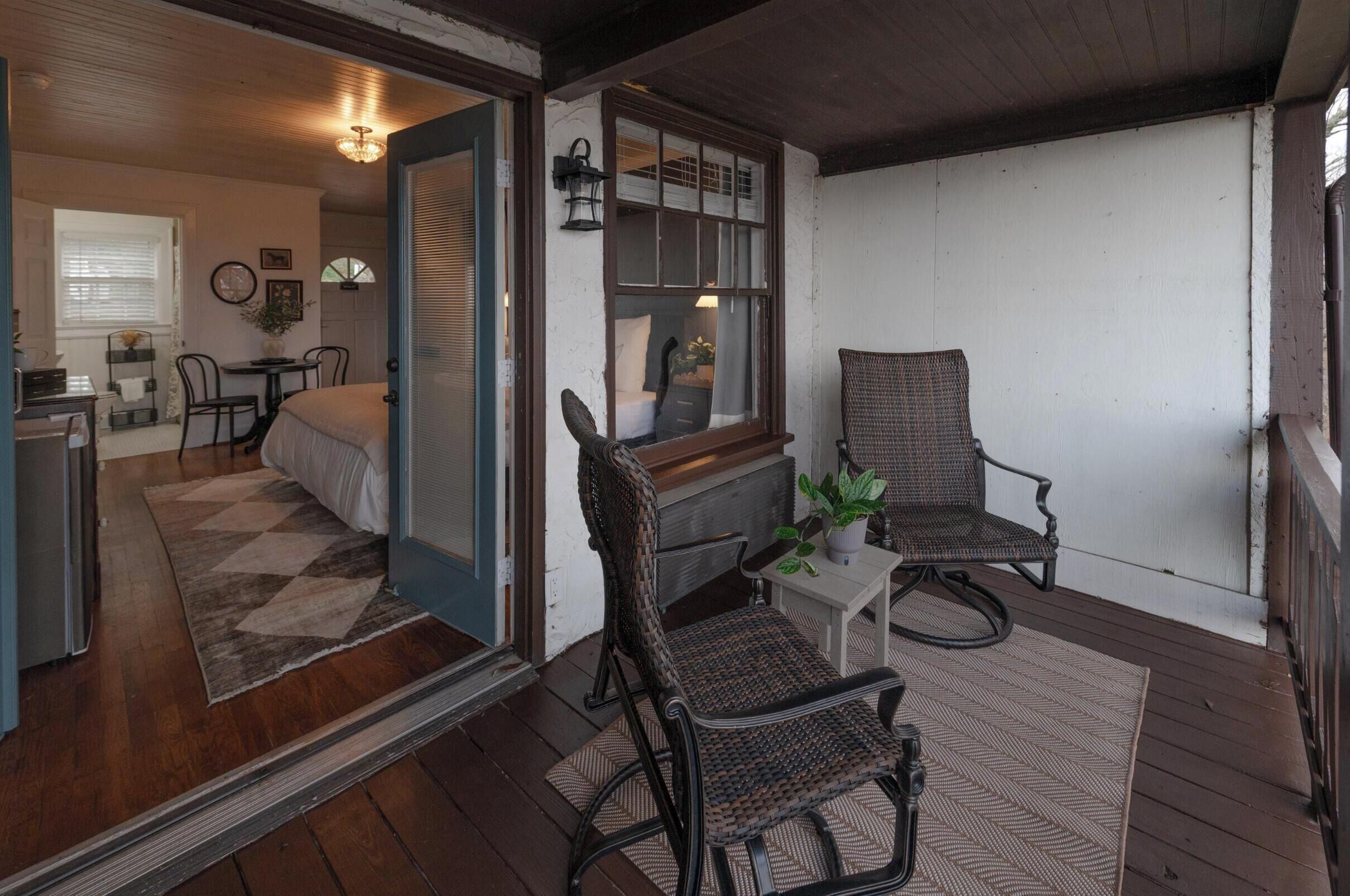 Une pièce confortable avec un lit, deux fauteuils en osier, une petite table et une fenêtre donnant sur un beau paysage.