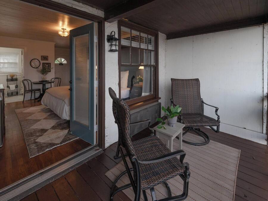 Une pièce confortable avec un lit, deux fauteuils en osier, une petite table et une fenêtre donnant sur un beau paysage.