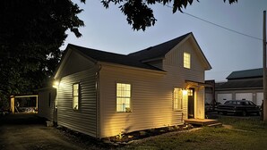 A two-story house with a garage, a driveway, and a well-lit front porch.