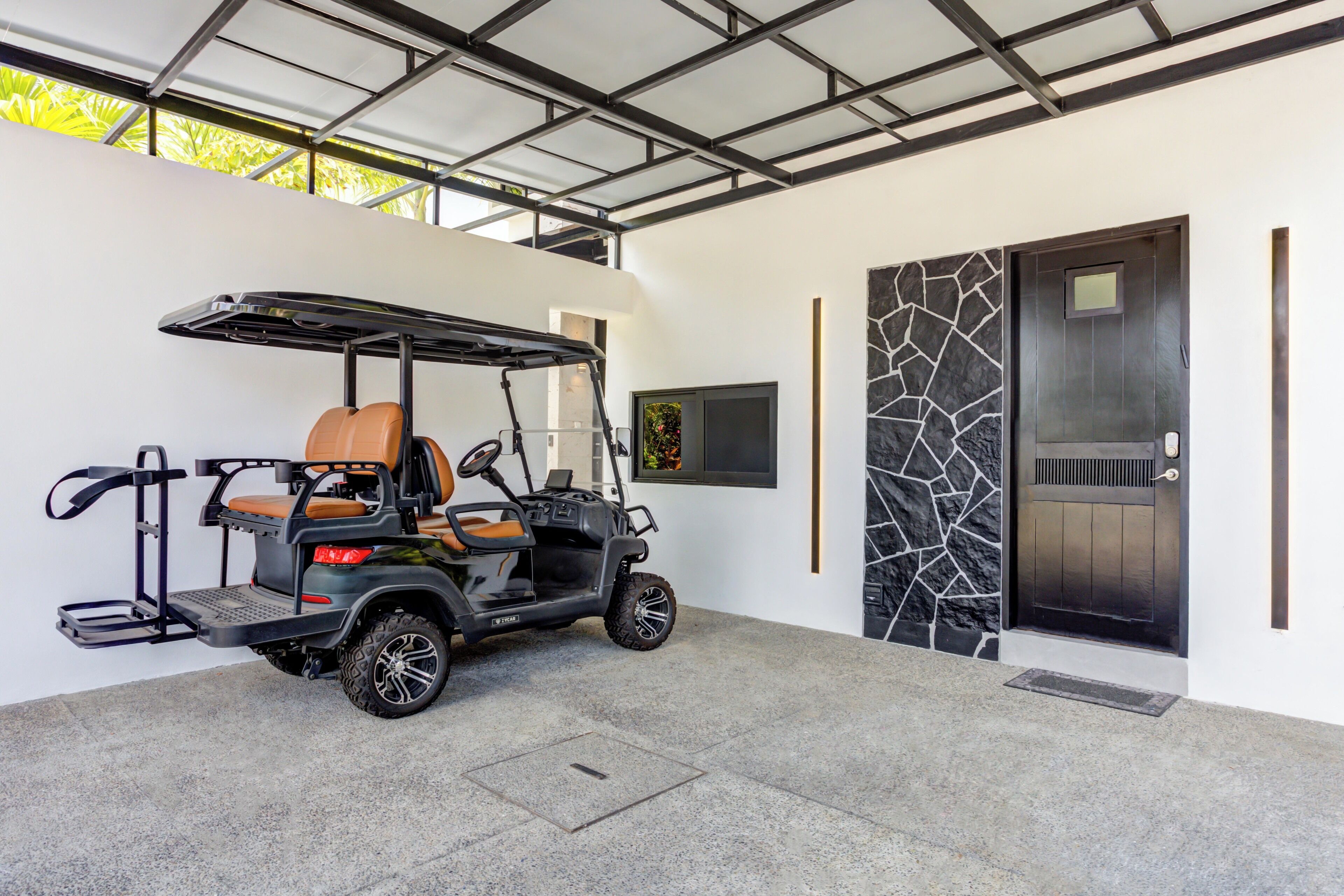 A modern building with a covered parking area, a golf cart, and a door with a stone-like pattern.