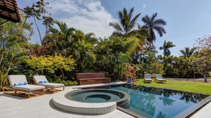 Una piscina con jacuzzi, rodeada de exuberante vegetación y palmeras.