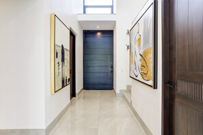 A hallway with a dark blue door, white walls, and two framed artworks on either side. - El Tigre Mariposa Villas (Nuevo Nayarit)