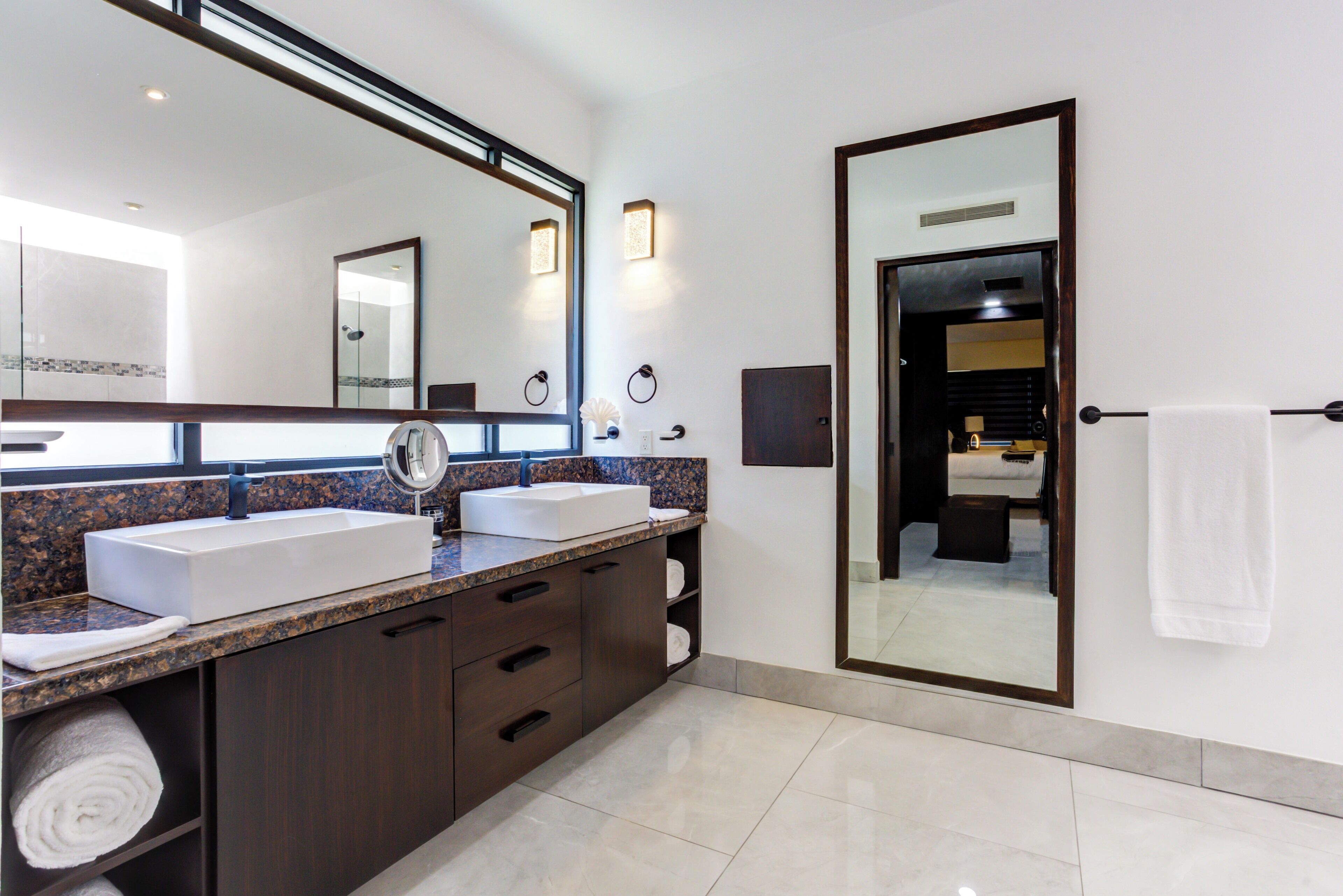 A modern bathroom with two sinks, dark wood cabinets, and a large mirror.