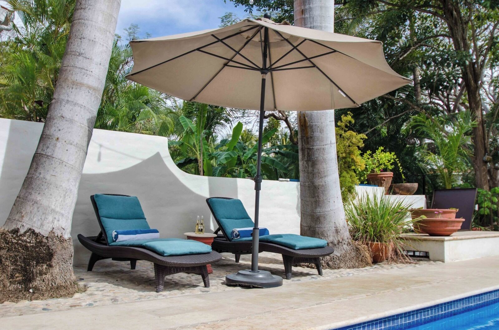 A poolside area with two lounge chairs and a large umbrella.