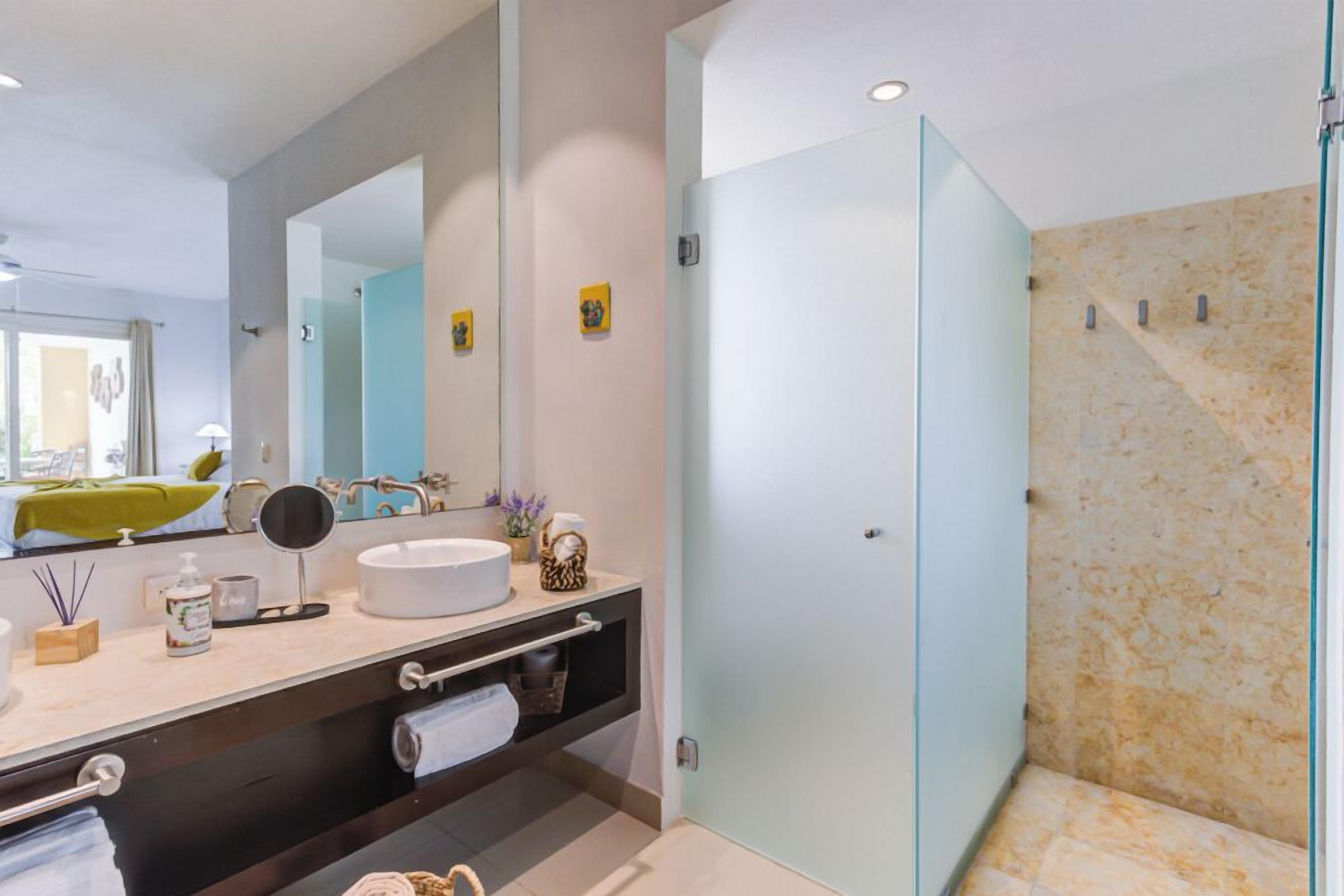 Une salle de bain moderne avec un grand miroir, un lavabo rond et une douche à parois de verre.