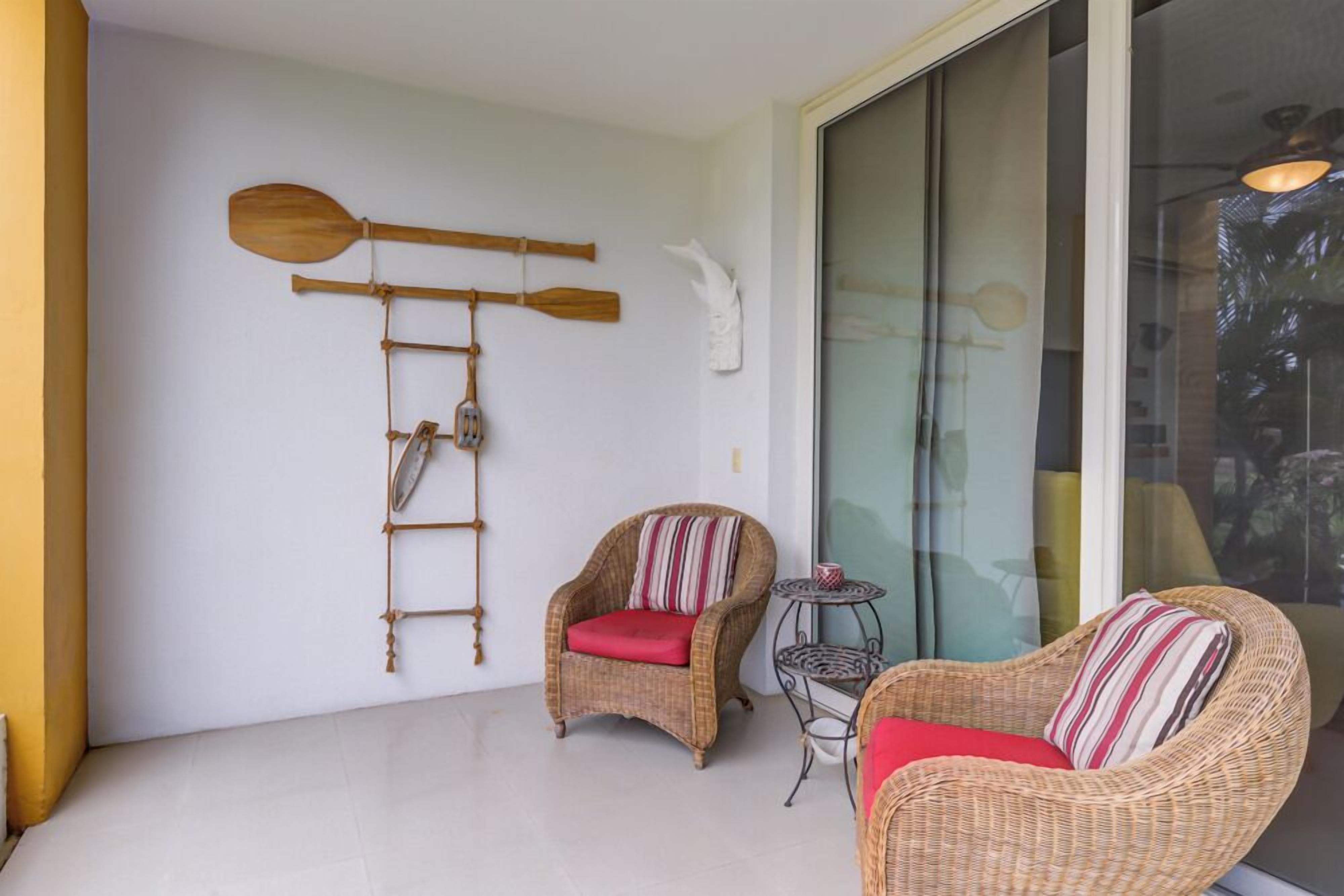 A room with wicker furniture, a ladder, and a wall-mounted paddleboard.
