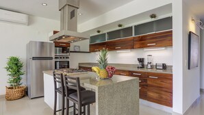Una cocina moderna con una isla central, electrodomésticos de acero inoxidable, armarios de madera y un horno empotrado.