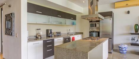 A modern kitchen with granite countertops, stainless steel appliances, and a central island.