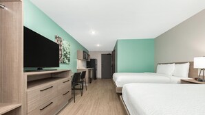 A hotel room with a bed, a desk with a chair, a television, and a microwave. - ECHO Suites Extended Stay by Wyndham Dallas Plano/Richardson (Plano)