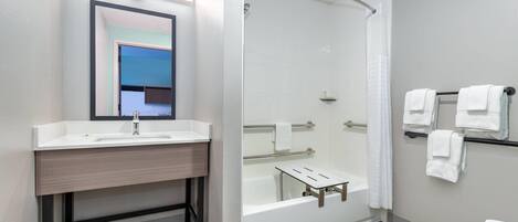 A modern bathroom with a glass-enclosed shower, a white sink, and a mirror above it.