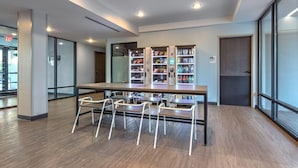 A modern indoor space with a long table and chairs, vending machines, and a glass door leading outside. - ECHO Suites Extended Stay by Wyndham Dallas Plano/Richardson (Plano)