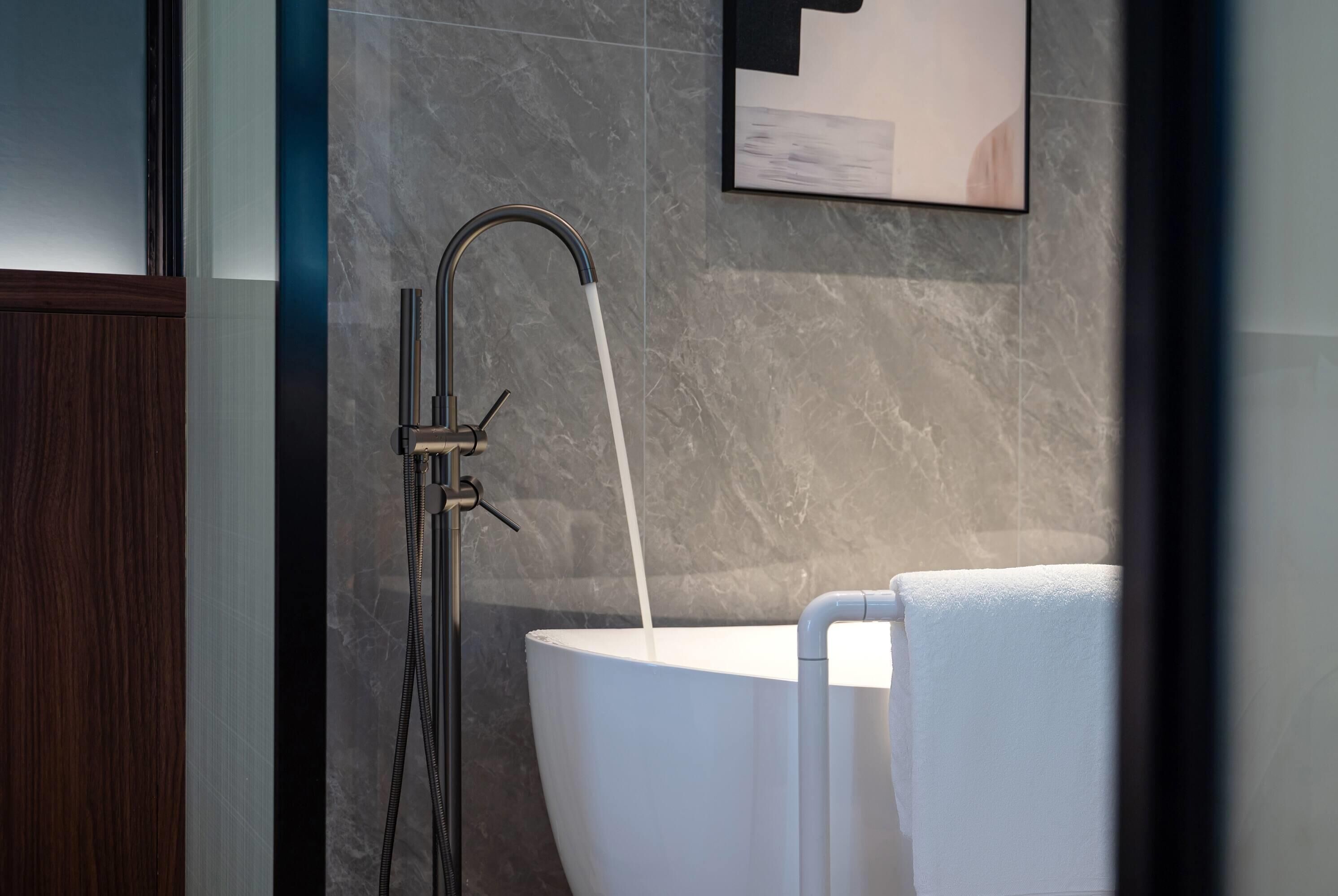 Un bagno moderno con una vasca freestanding, una doccetta e un porta asciugamani.