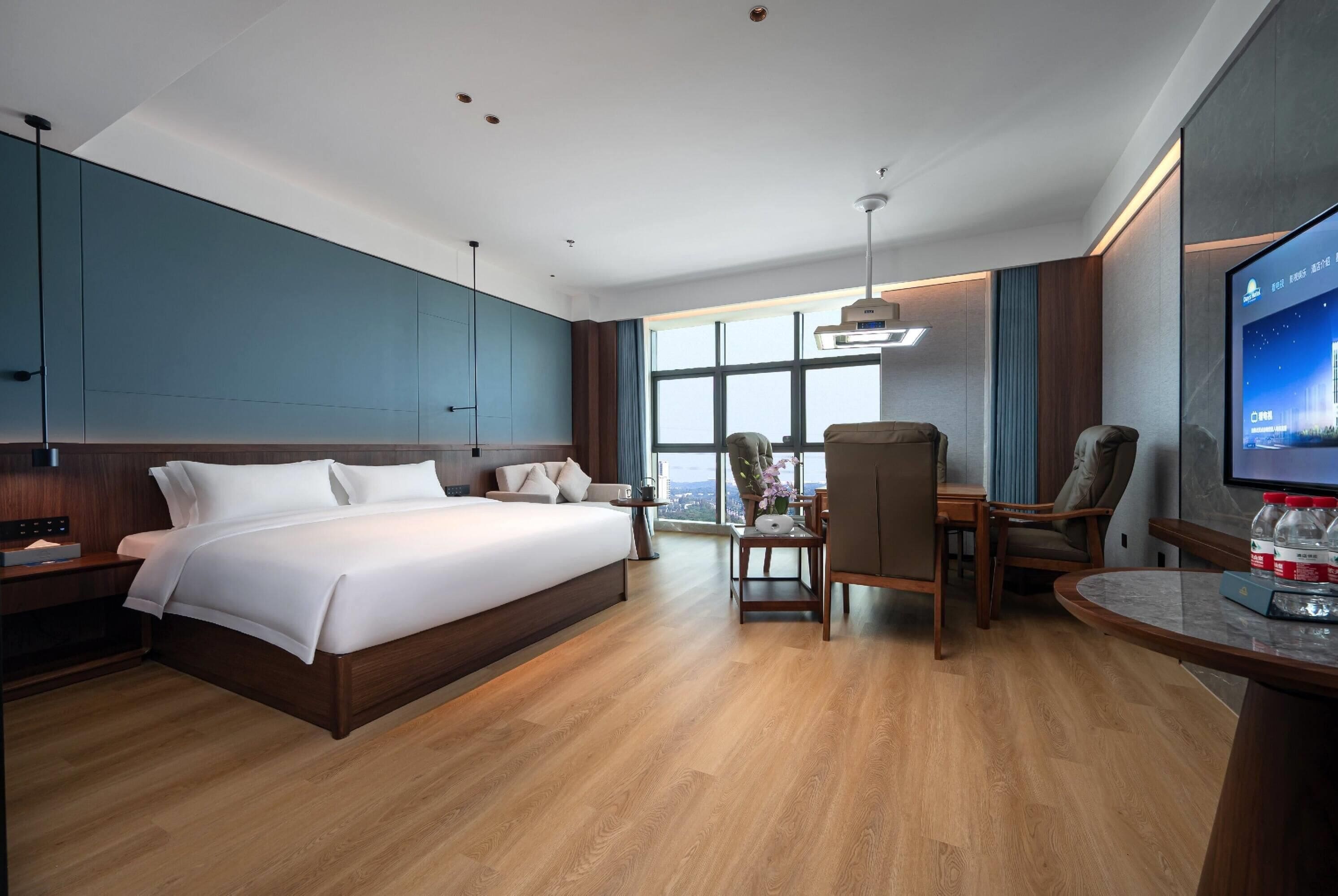 Una habitación de hotel moderna con una cama grande, un escritorio y una televisión.