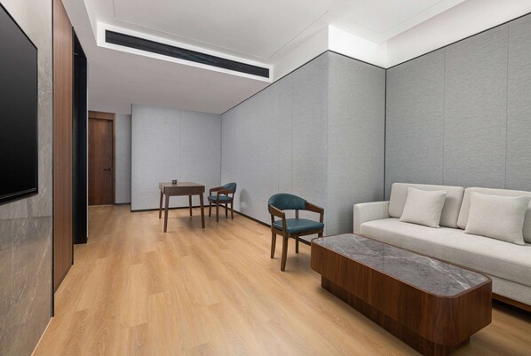 A modern living room with a wooden floor, a sofa, a coffee table, and two chairs. - Days Hotel By Wyndham Changsha East (Changsha)