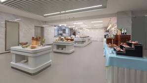 Un moderno vestíbulo de hotel con suelo de mármol, mobiliario contemporáneo y una mesa de buffet.