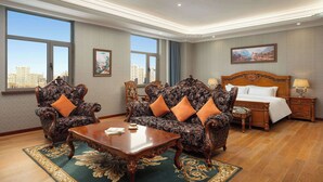 A hotel room with a large bed, two ornate armchairs, a wooden coffee table, and a view of the city through large windows. - Days Hotel By Wyndham Harbin Qunli (Harbin)