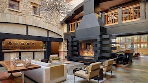 Amplio espacio interior con pared de piedra, chimenea y modernos arreglos de asientos.