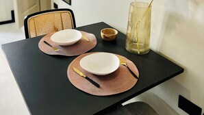 A dining table with placemats, plates, and cutlery, a vase with pampas grass, and a wall clock. - Charming studio with WiFi and AC in enchanting Il-Furjana (Il-Furjana)